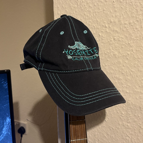 A black hat with teal stitching and Yosemite logo